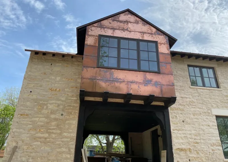 Copper metal panel facade on a stone building for Roof Repair in Price