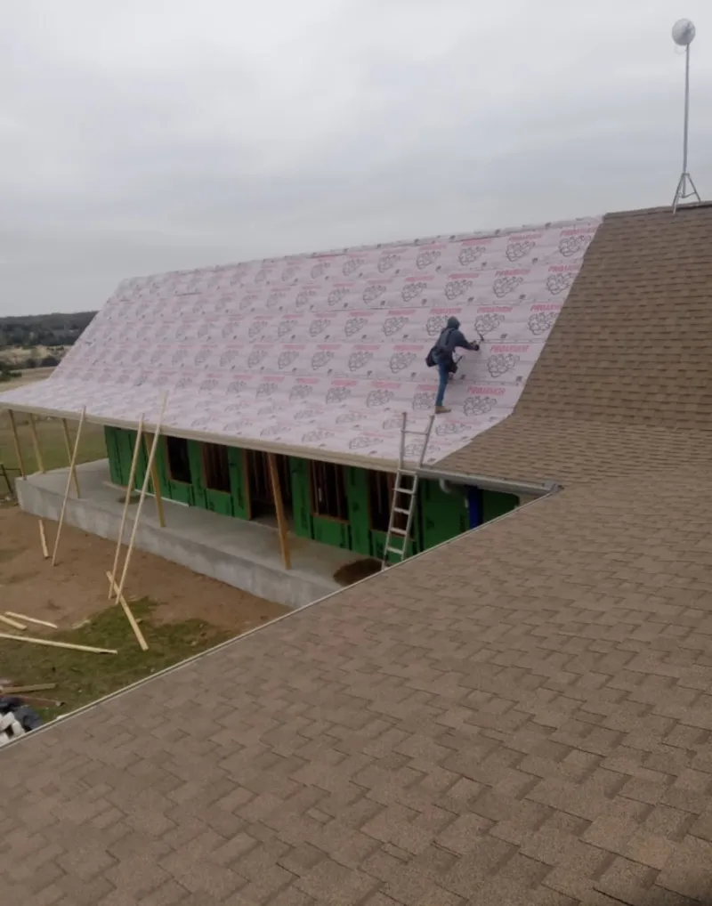 Worker preparing underlayment for a metal roof installation in Price